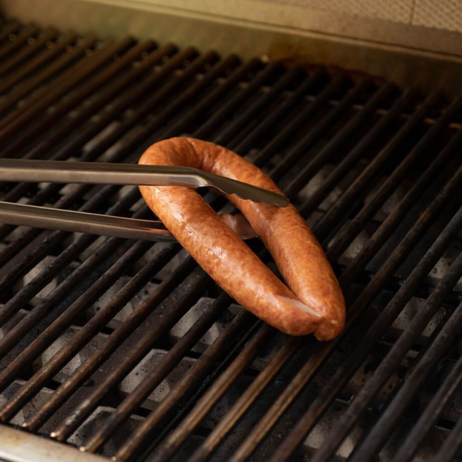 Kielbasa with tongs on a grill