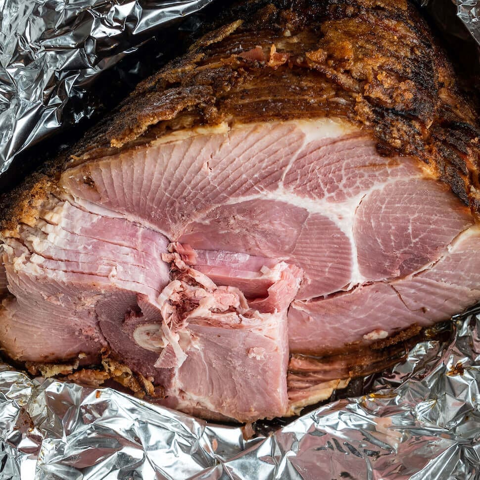 Cooked spiral cut ham wrapped in tin foil