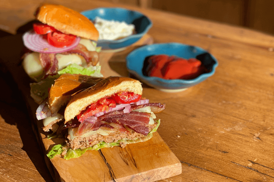 Pork and bacon burger cut in half on a wood cutting board