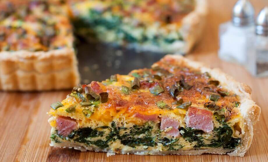 a slice of ham and cheese quiche on a table